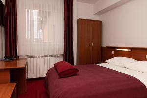 Un dormitorio con una cama con una almohada roja. en Hotel Mirni Kutak, en Otočac