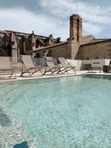 einen Pool mit Stühlen und ein Gebäude in der Unterkunft Hotel Palau Macelli in Castelló d'Empúries