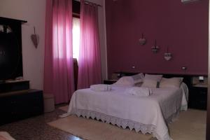 um quarto com paredes cor-de-rosa e uma cama com lençóis brancos em B&B Piazza Municipio em San Vito