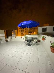 un patio con una mesa y una sombrilla azul en Apartamento Independiente 1 dormitorio cama Queen, en Lima