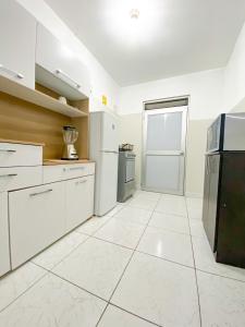 Apartamento Independiente 1 dormitorio cama Queen في ليما: مطبخ فارغ مع دواليب بيضاء وثلاجة