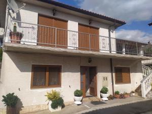 a white house with a balcony and potted plants at Tomić in Novi Vinodolski
