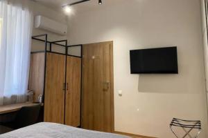 a bedroom with a bed and a flat screen tv on the wall at Villa SOFI in Lviv