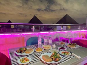 a table with plates of food on it with pyramids at Best View Pyramids Hotel in Cairo