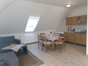a living room with a table and a kitchen at Föveny Apartman in Balatonudvari