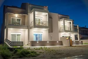 een groot wit huis met 's nachts lichtjes bij Aelia Luxury Apartments in Nikiti