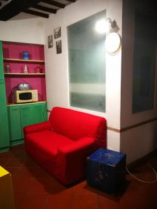 a red couch in a living room with a microwave at ALLOGGIO S.ANNA in Isola del Giglio