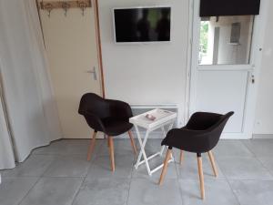 Saint-MesminにあるStudio Le Mesminoisのテレビ付きの客室で、椅子2脚とテーブル1台が備わります。