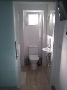 a bathroom with a toilet and a sink and a window at La Isla habitacion independiente con baño privado y jardín in Santiago de la Ribera