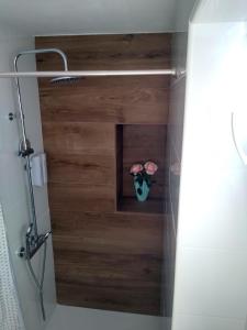 a bathroom with a wooden wall and a vase with flowers at La Isla habitacion independiente con baño privado y jardín in Santiago de la Ribera +21 photos