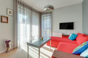 salon z czerwoną kanapą i stołem w obiekcie Comfort Apartments Kwartał Kamienic w Gdańsku