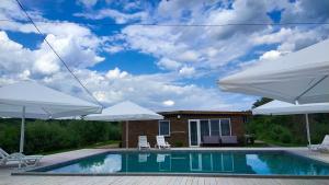 a pool with two white umbrellas and a house at Kambodzha na Dynae in Vylkove
