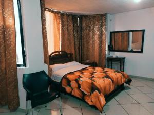 1 dormitorio con cama, silla y cortinas en Hostal Ajavi del Sur, en Sozoranga