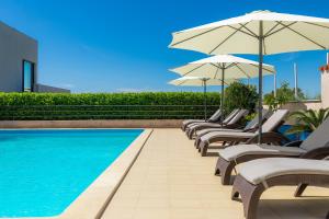 a row of chairs and umbrellas next to a swimming pool at Astinian apartments Jadranka in Pula