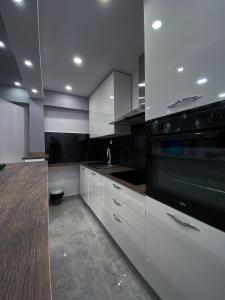 eine Küche mit weißen Schränken und einem schwarzen Gerät in der Unterkunft Apartment Carpe Diem in Koper