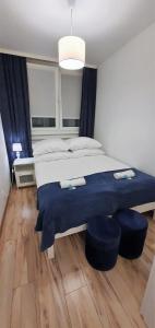 ein Schlafzimmer mit einem großen Bett mit zwei blauen Ottomanen in der Unterkunft Apartament Łąkowa in Polanica-Zdrój