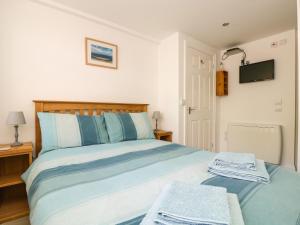 a bedroom with a bed with blue and white sheets at Seascape in Porthcurno