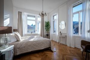 ein weißes Schlafzimmer mit einem Bett und zwei Fenstern in der Unterkunft Boutique Charme Apartment Ricarda in Baden-Baden