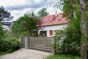 une maison avec une clôture et un toit rouge dans l'établissement Füge Vendégház Sajkod, à Tihany