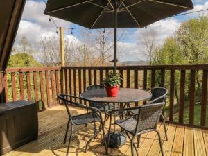einen Terrassentisch und Stühle mit Sonnenschirm auf einer Terrasse in der Unterkunft 59 Valley Lodge in Callington