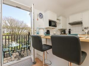 a kitchen with a table and chairs and a balcony at Tater-du in Porthcurno
