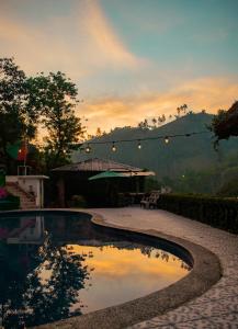 a swimming pool with a sunset in the background at Viñas Hotel in Lanquín