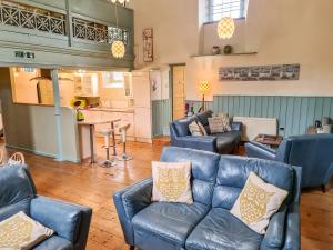 a living room with blue leather furniture and a kitchen at Rainforest Chapel in Longney