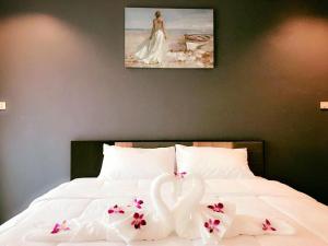 two white swans sitting on a bed with flowers at Supachai Inn in Ban Ba Ngan