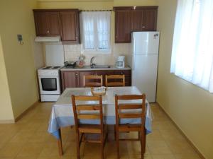 a kitchen with a table with chairs and a white refrigerator at Akti Zaga Apartments in Koroni