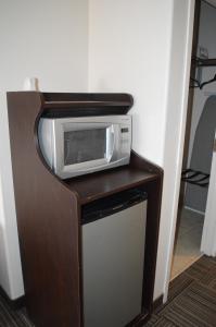 a microwave sitting on top of a wooden stand at Auberge MacDonald Guest Inn in Iroquois Falls