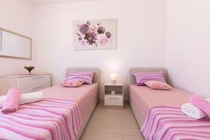 two beds in a room with pink and purple sheets at Apartment Oleander in Punat