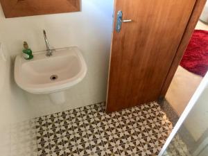 a bathroom with a sink and a wooden door at Loft Estrada Real in Petrópolis
