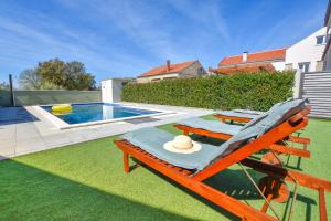a deckchair with a hat sitting on a lawn next to a pool at Villa Pave in Pakoštane