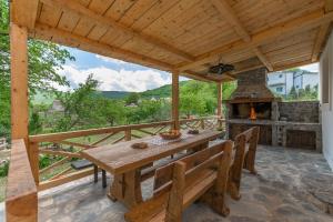 a wooden table and bench on a deck with a fireplace at House Mali dvori in Krivodol