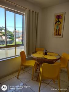 a dining room with a table and chairs and a window at AP PRAIA - Cond Vog João de Góis 2 quartos com AR in Ilhéus