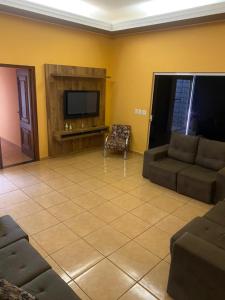 a living room with a couch and a tv at Casa dos Carvalhos Rua do sabiá 25 coab 1 in Olímpia