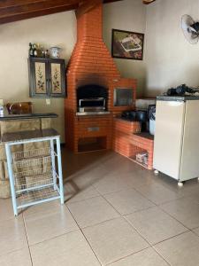 a kitchen with a refrigerator and a brick fireplace at Casa dos Carvalhos Rua do sabiá 25 coab 1 in Olímpia