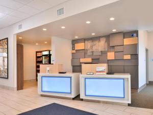 a waiting area in a hospital lobby with two monitors at Holiday Inn Express & Suites - Brighton South - US 23, an IHG Hotel in Brighton