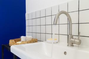 a sink in a bathroom with a white tiled wall at Stylish loft in the city center in Trieste