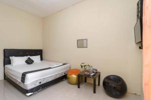 - une petite chambre avec un lit et une table dans l'établissement Madinah House Syariah Mitra RedDoorz, à Depok
