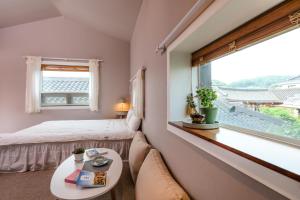 Haengok Guesthouse في جيونجو: غرفة نوم بسرير وطاولة ونافذة