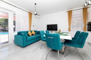 a living room with a blue couch and a table and chairs at Villa Beganović in Krk