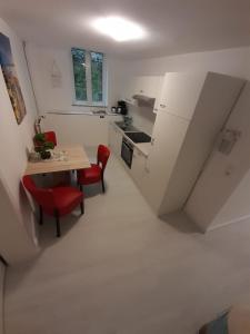 a small white kitchen with a table and red chairs at Flensburg Zentrum 69 01 in Flensburg