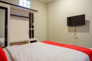 a bedroom with a bed and a flat screen tv at RedDoorz Plus near Jogja City Mall 5 in Yogyakarta