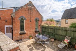 a patio with a table and chairs in front of a brick building at Old Chapel in Cheltenham