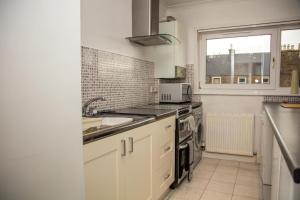 a kitchen with white cabinets and a sink and a window at Beach Walk Apartment in Broughty Ferry