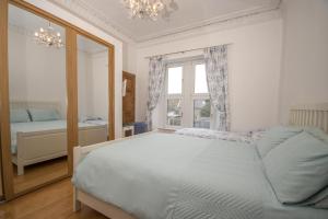 a bedroom with a large bed and a mirror at Beach Walk Apartment in Broughty Ferry
