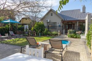 a patio with chairs and a pool in front of a house at De Akker Guest House Oudtshoorn in Oudtshoorn