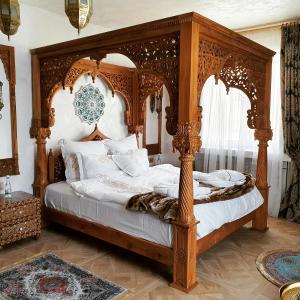 a bedroom with a wooden canopy bed with white pillows at TAJ Royal APARTMENT in Bucharest