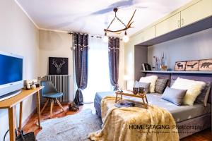 a bedroom with a bed and a desk and a television at Hostdomus - Il Cerbiatto Apartment in Sestriere